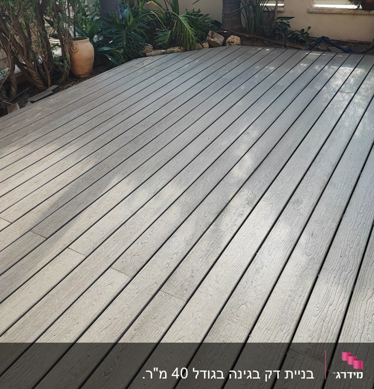 דק עץ בגינה עם עציצים וצמחים מסביב